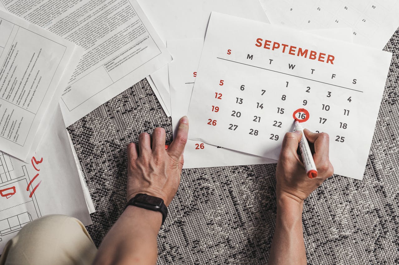 The Art of Drawing Readers In: Your attractive post title goes here Hands holding a calendar with September dates encircled, surrounded by documents on a carpet.